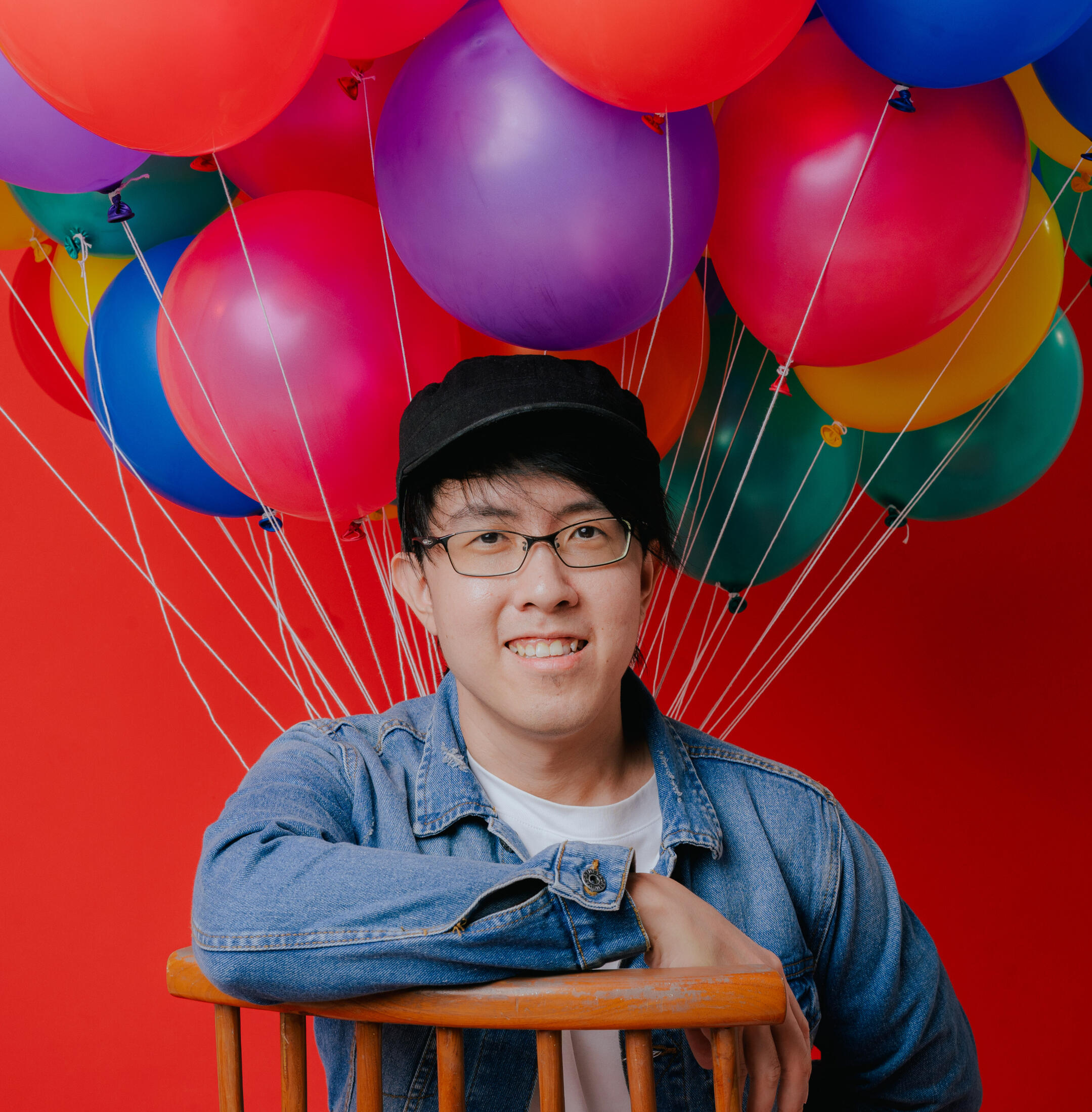 A picture of me in a white t-shirt with denim outerwear on a colourful backdrop.